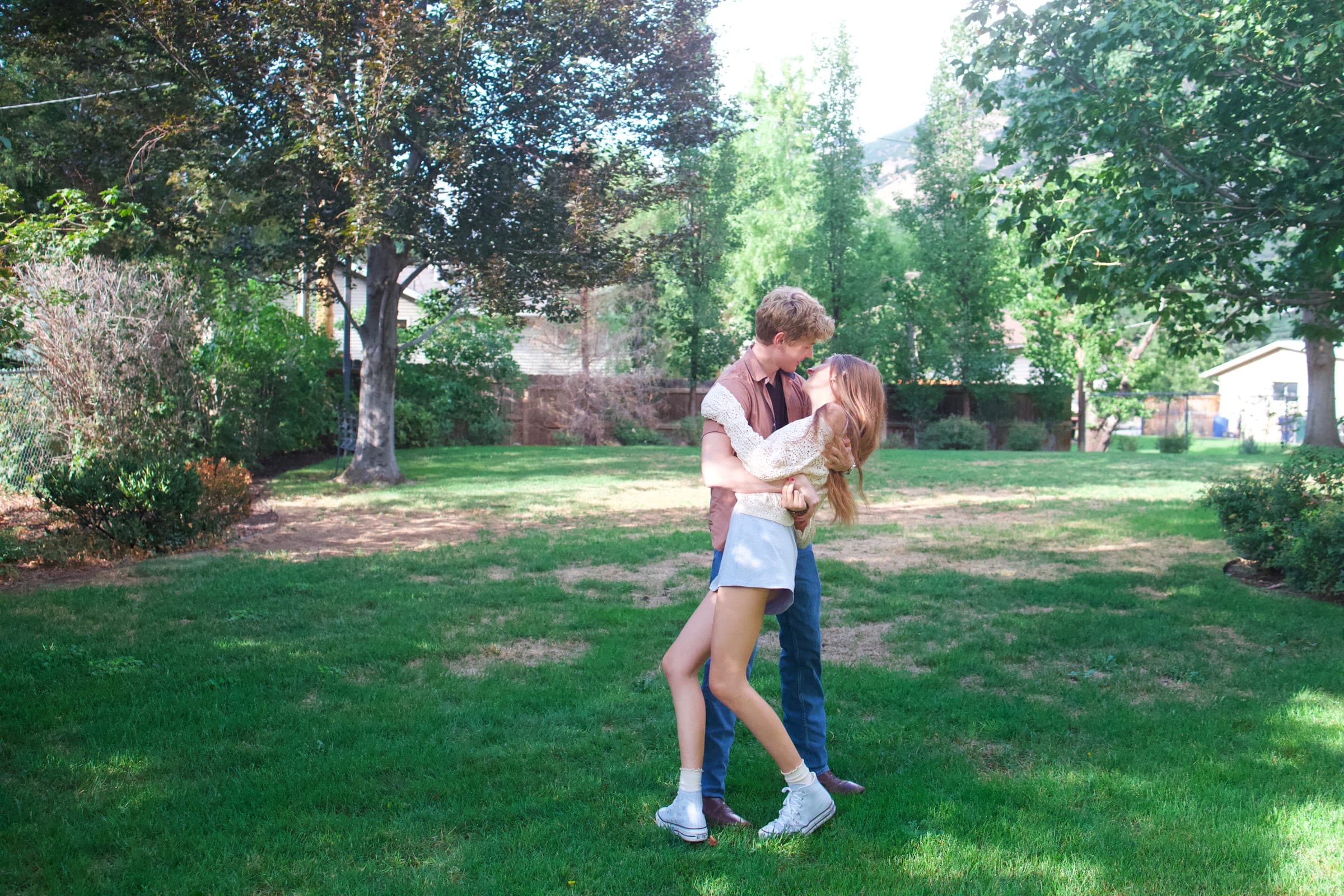 Tyler lifting Molly in a hug in the middle of a big green lawn